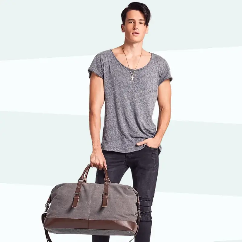 Grand sac de voyage vintage en toile gris pour homme tenu à la main