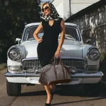 Grand sac de voyage vintage en toile pour femme moderne Grand sac de voyage vintage en toile pour femme moderne quinporte un foulard sur le tête et devant une voiture
