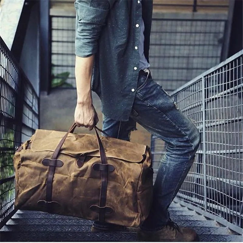 Grand sac voyage en toile style vintage pour escapades et voyages d'affaires porté à la main par un homme