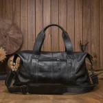 Sac de voyage en cuir noir face sur fond bois Sac de voyage en cuir noir face sur fond bois